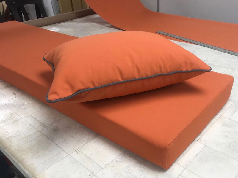 A set of new bespoke outdoor cushions covered in a contemporary orange fabric with grey piping